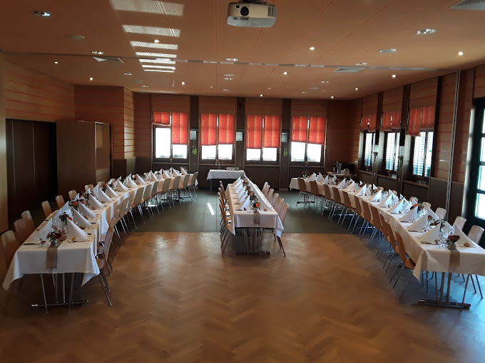 Grand salle avec tables longues en U dressées pour un banquet dans le restaurant Maison de Ville à Vuippens