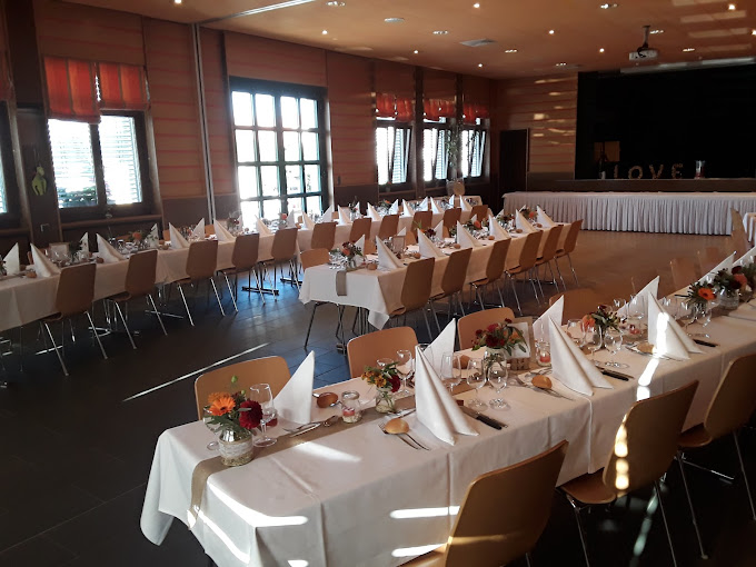 Grande salle avec tables longues dressées pour un banquet dans le restaurant Maison de Ville à Vuippens