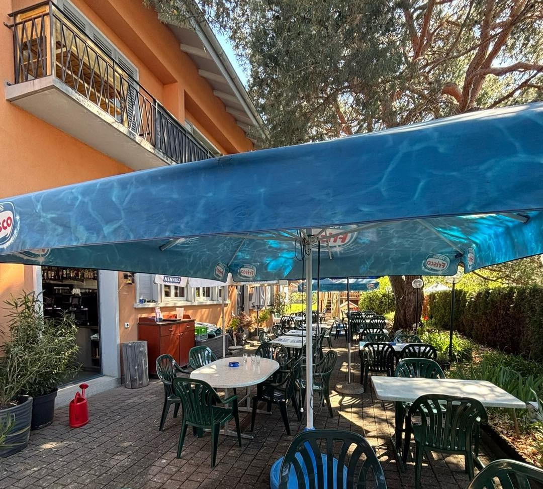 Terrasse du restaurant avec tables dressées à l’ombre des parasols
